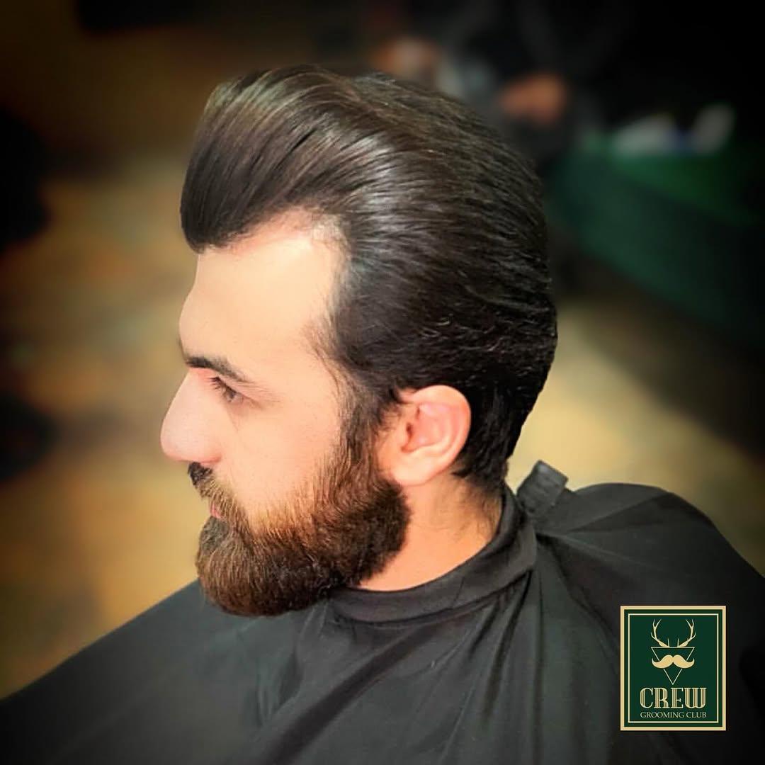Slicked-back hairstyle paired with a sculpted beard trim at Crew Barbers West London
