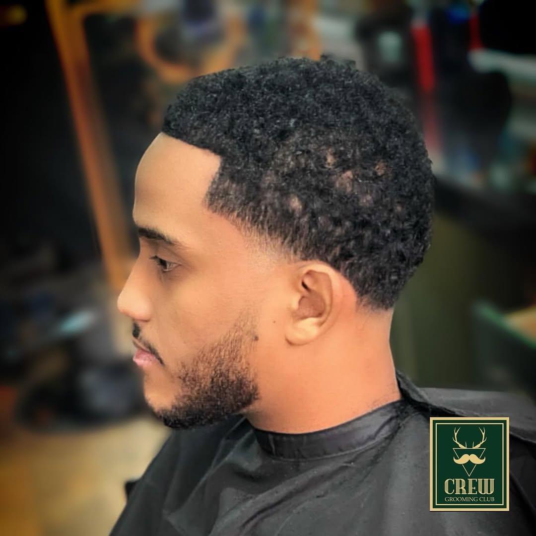 Natural curls left long on top over a clean mid fade — finished by Crew Barbers Isleworth